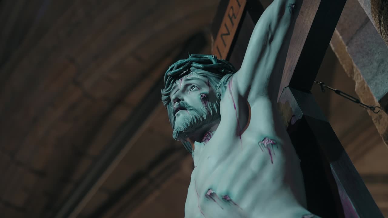 close up of crucified Jesus statue lit from below inside a dimly lit church interior