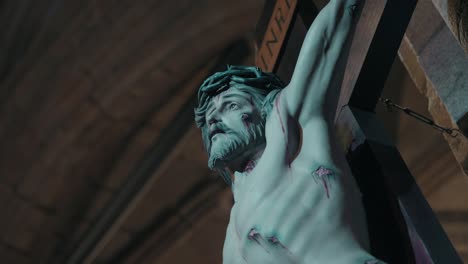 close up of crucified jesus statue lit from below inside a dimly lit church interior