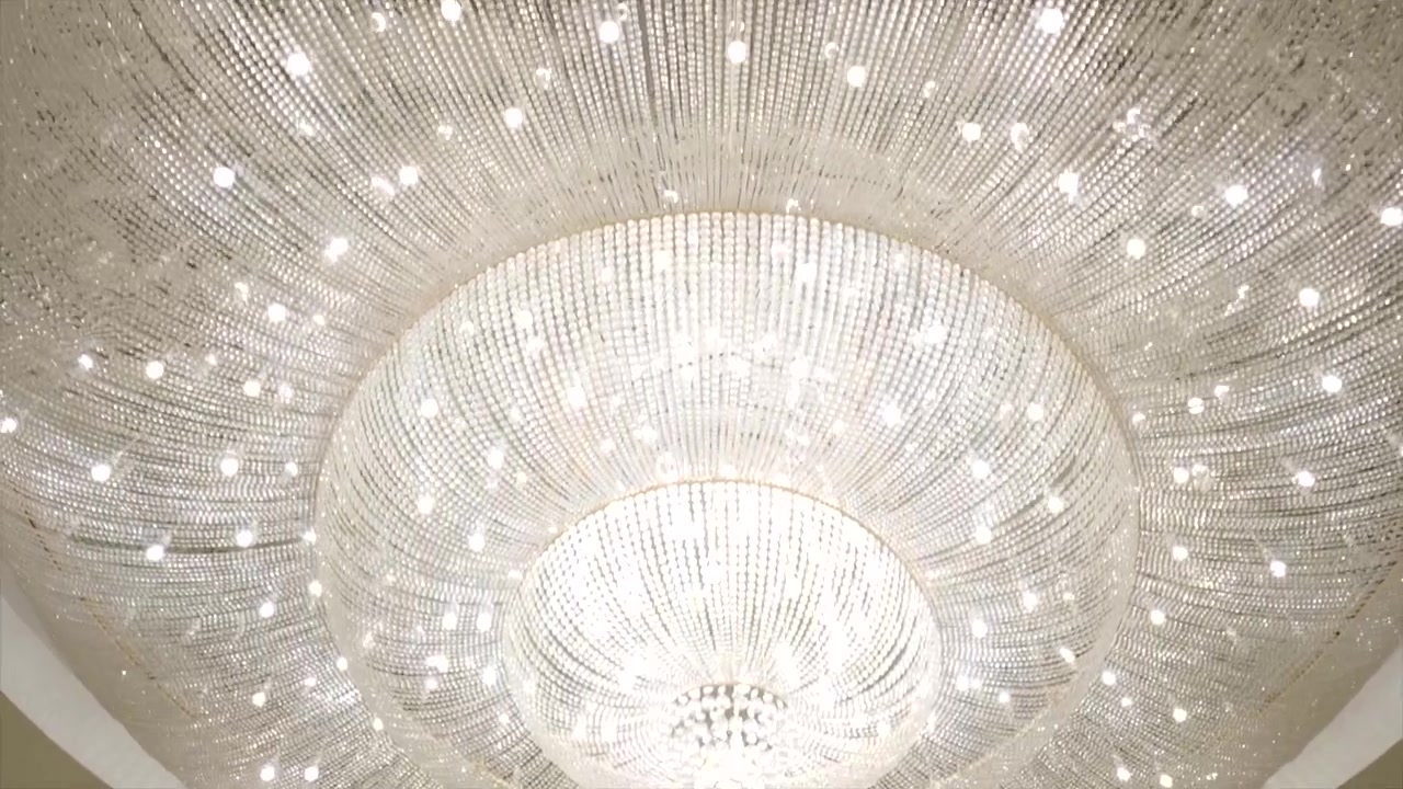 Elegant close-up view of a sparkling crystal chandelier hanging from the ceiling, reflecting brilliant light and adding luxury, sophistication, and timeless beauty to the interior.