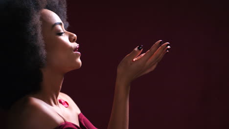 mujer negra, soplando pétalos de rosa en la piel