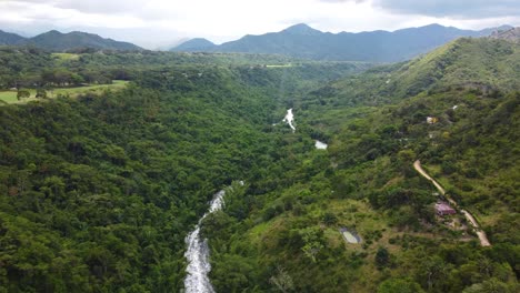 a 4k drone shot flying in a light rain storm over the countryside of a small village in colombia.