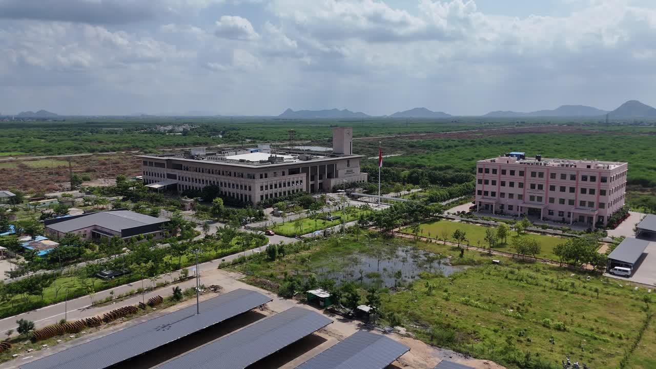 Drone shot capturing government building with greenery and distant urban structures nearby in Vijayawada Amaravati