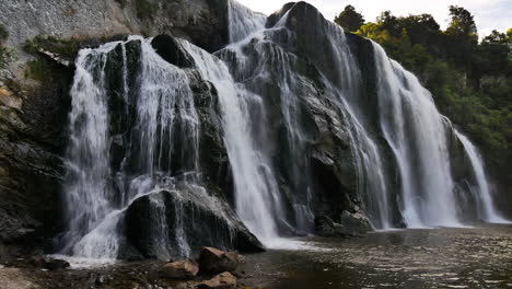 Toma-Panorámica-De-La-Gigantesca-Cascada-Waihi-Que-Desemboca-En-Un-Lago-Idílico-En-Nueva-Zelanda,-Manawatu-wanganui