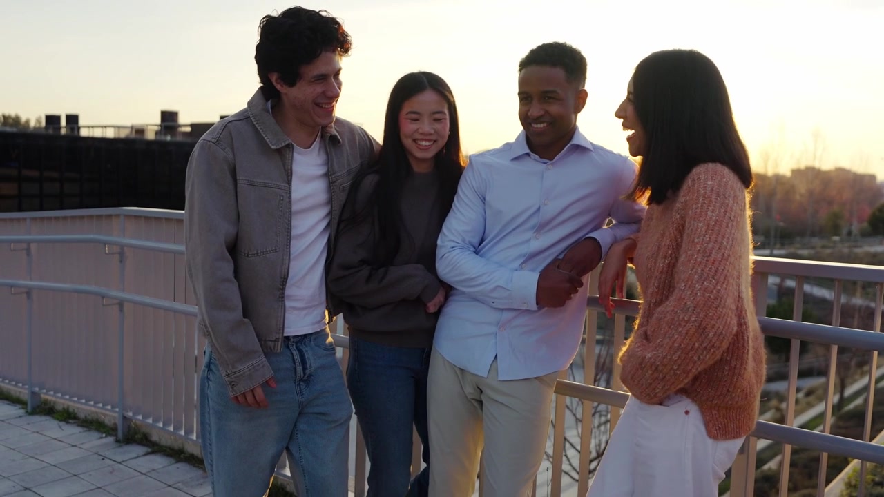 Grupo diverso de amigos felices hablando y riendo al atardecer.