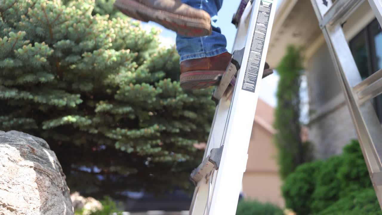 Man climbs a ladder on a job site to repair a roof