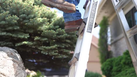 man climbs a ladder on a job site to repair a roof