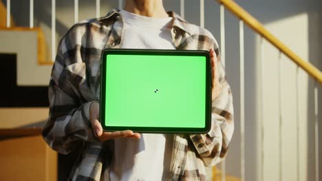 a woman holds a tablet with a green screen in her hands, close-up