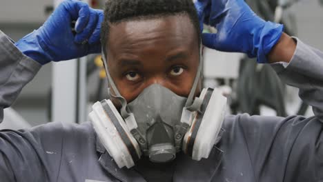 mecánico de automóviles afroamericano que se pone una máscara facial