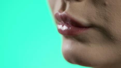 woman eating strawberry in neon lighting, close-up of face and mouth, green background