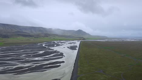 vista aérea de un río trenzado que fluye hacia el océano en un día nublado en islandia
