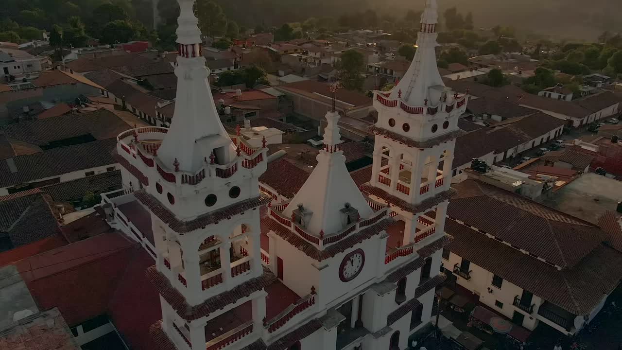 San Cristobal Church Bell Tower With Clock On Front Facade At Sunset In Mazamitla, Jalisco, Mexico. - aerial ascend
