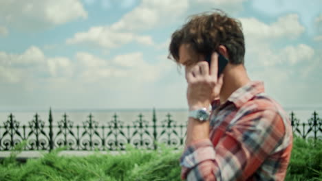 hombre con teléfono inteligente de pie en el camino en el parque