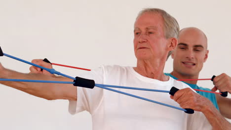 trainer and old man exercising with resistance band