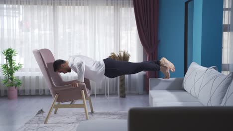 sportsman doing push-ups briskly using sofa and armchair.