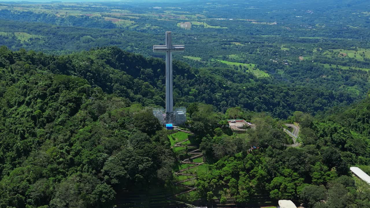 Overhead dolly zoom aerial emphasizing the towering Mt. Samat National Shrine, framed by lush forested hills and expansive mountain views in Pilar, Bataan, Philippines