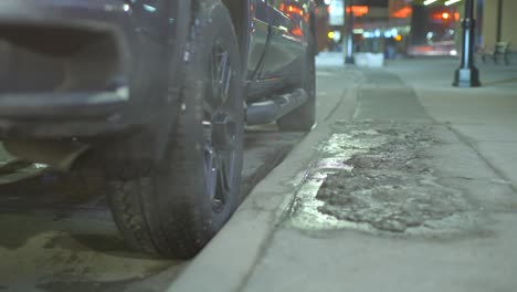 primer plano de las ruedas traseras de un camión mientras da marcha atrás en un lugar de estacionamiento al lado de un bordillo