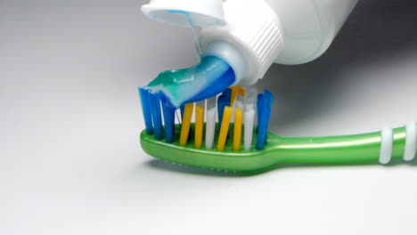 toothpaste is applied to a green toothbrush