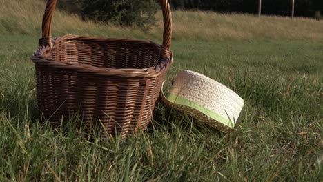 straw hat and woven basket left in the grass zoom out shot