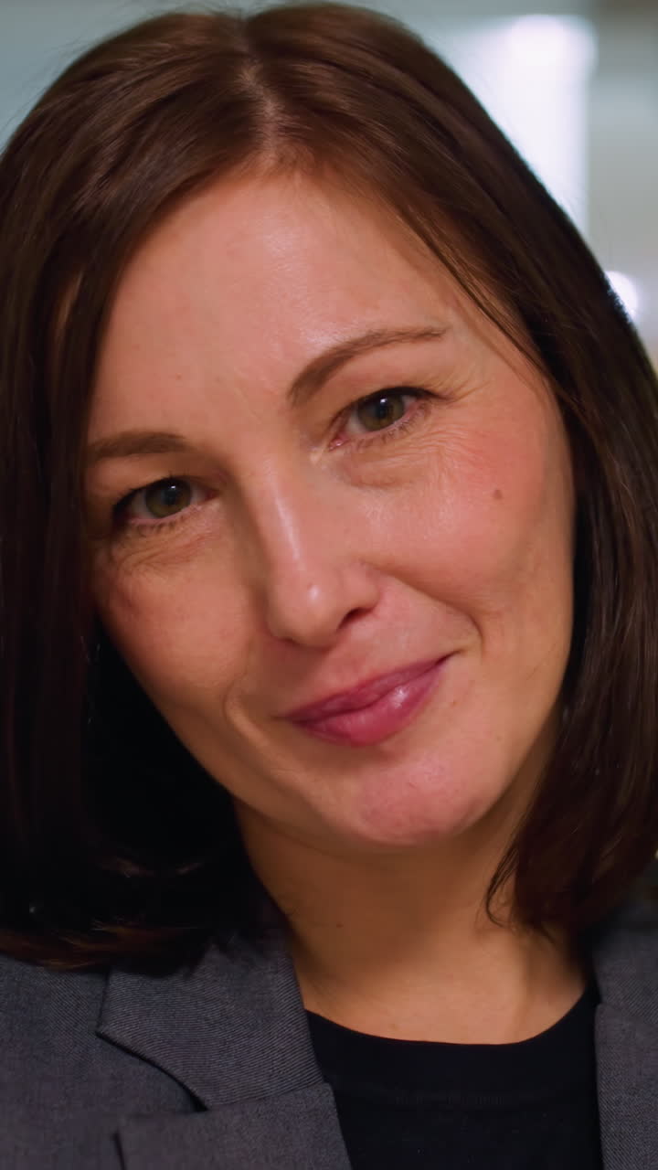 Confident professional woman in formal blazer standing with arms crossed and holding notebook in modern office corridor, expressing authority, calmness, and readiness for business or leadership tasks