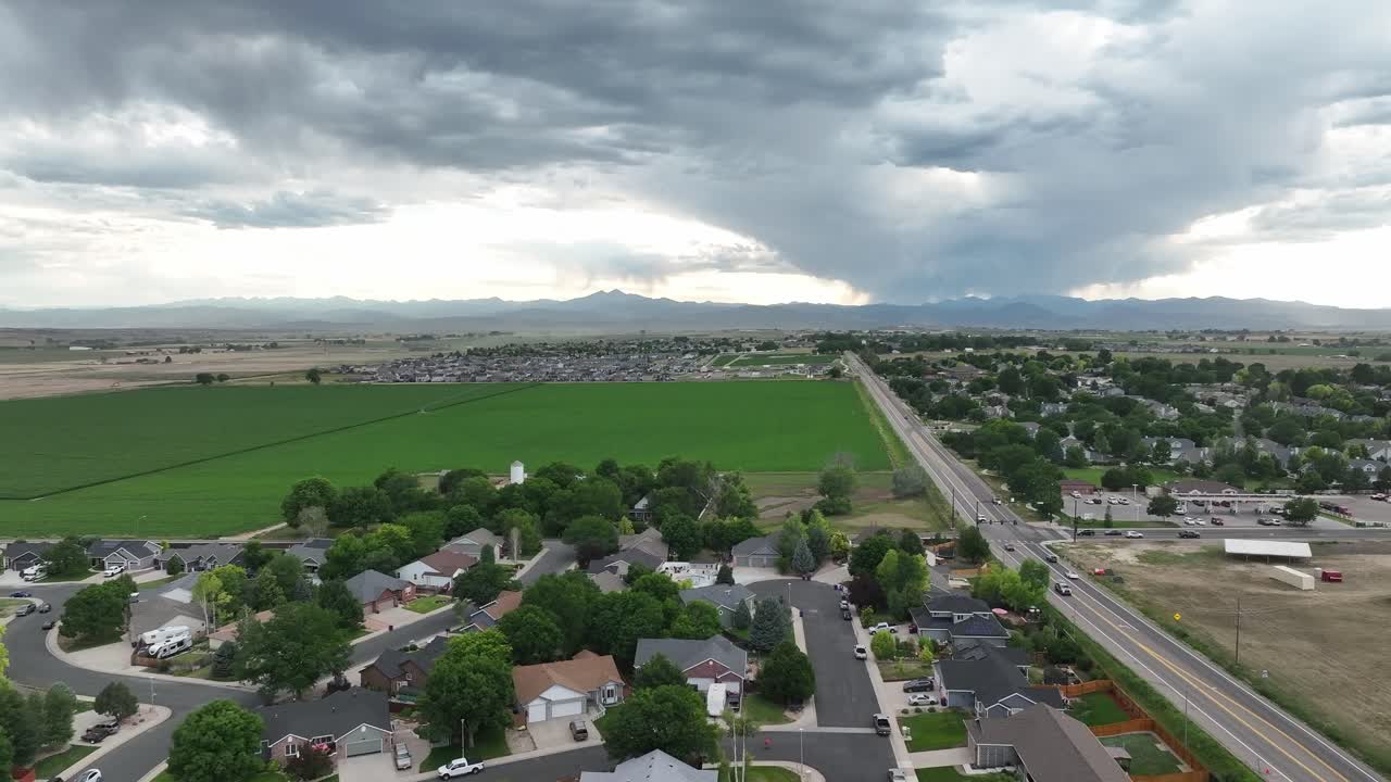 Rekaman udara jalan keluar kota Johnstown Colorado dengan pegunungan di latar belakang. Bidikan pengantar properti