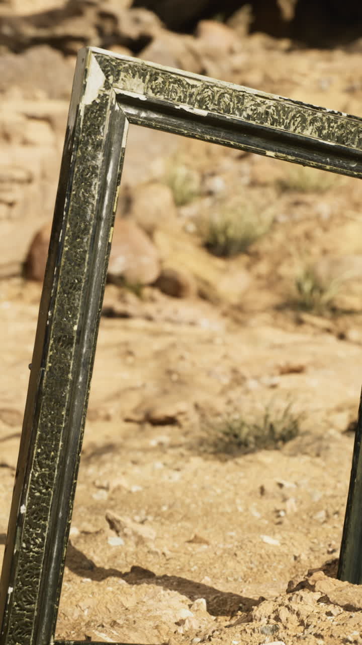 Desert landscape features an ornate frame standing amidst rocky terrain