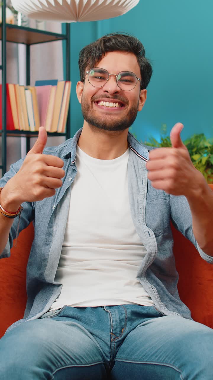 joven indio feliz mirando con aprobación a la cámara muestra los pulgares hacia arriba como un signo positivo buenas noticias
