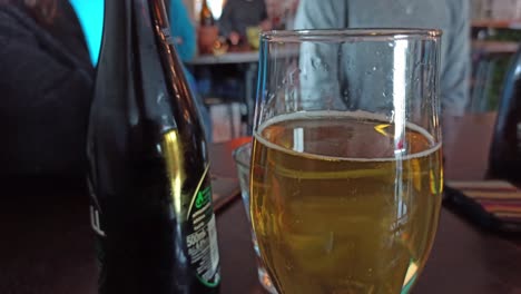 a close up shot of a glass of cider with people out of focus in the background