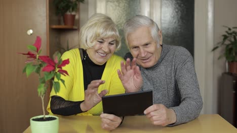 Bonita-Pareja-De-Ancianos-Maduros-Haciendo-Una-Videollamada-Con-Una-Tableta-En-Casa