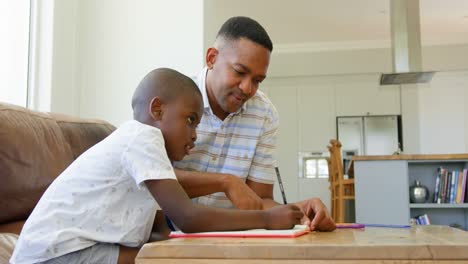 Side-view-of-young-black-father-helping-his-son-with-homework-in-a-comfortable-home-4k