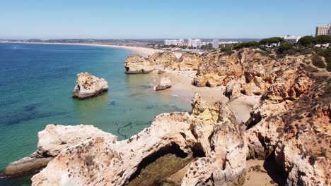 playa praia dos tres irmaos, algarve, portugal - vista aérea de drones de la costa con acantilados rocosos, turistas y hoteles