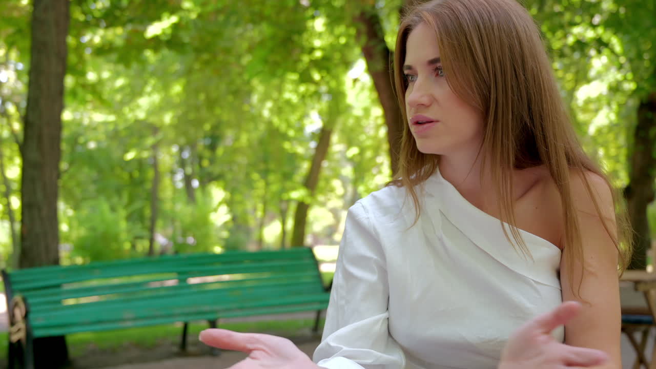 Brunette woman talking in the park while drinking coffee