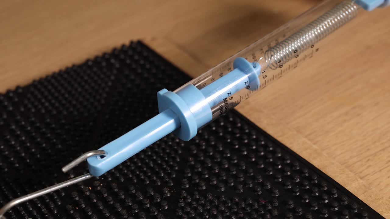 A spring scale measures friction on a textured surface, highlighting mechanical principles in a controlled environment with natural lighting