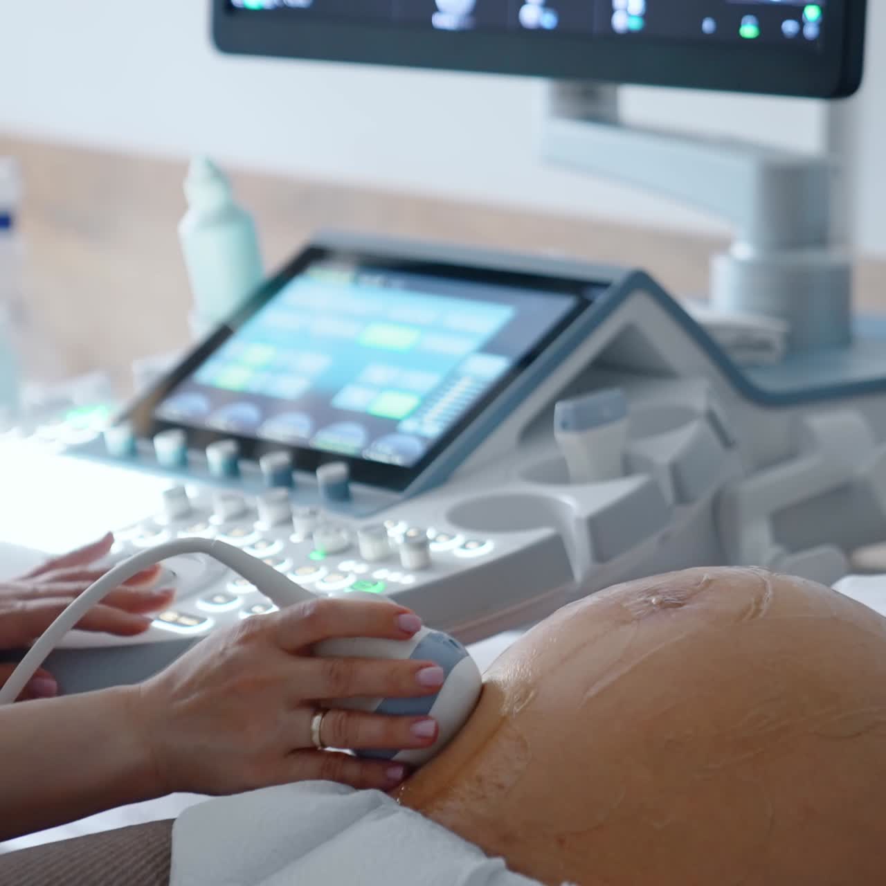 Gestante caucasiana fazendo um ultrassom. Uma médica não reconhecida move o dispositivo ultrassônico em sua grande barriga redonda.