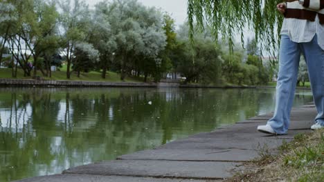 woman using phone in a park by the pond