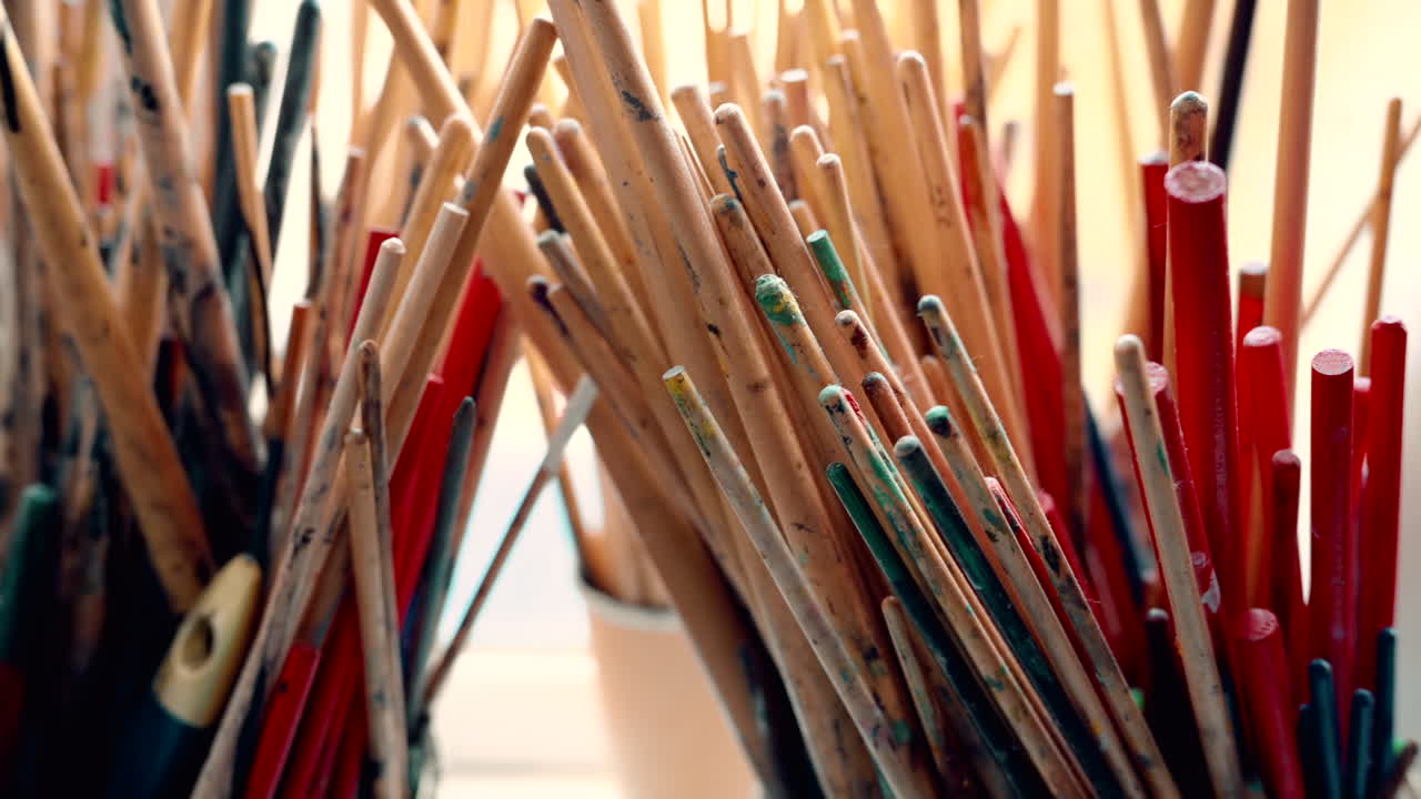 Close up of multiple dirty paint brushes in cups