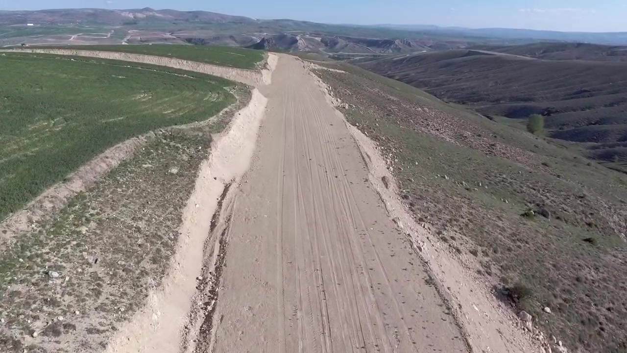 Vista aérea de un camino de tierra atravesando un paisaje rural.