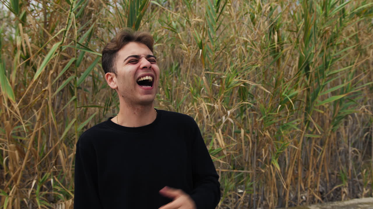 소년은 농촌에서 농담을 들었을 때 식물 사이에서 큰 소리로 웃습니다.