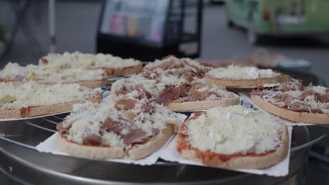 cheese-and-ham-sandwiches-on-an-aluminium-turntable,-people-in-a-blurred-background