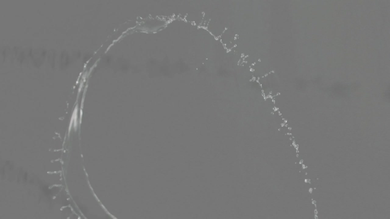 Strato di liquido propulso che si inarca dall'alto a sinistra, assottigliandosi e rompendosi in gocce per tensione superficiale