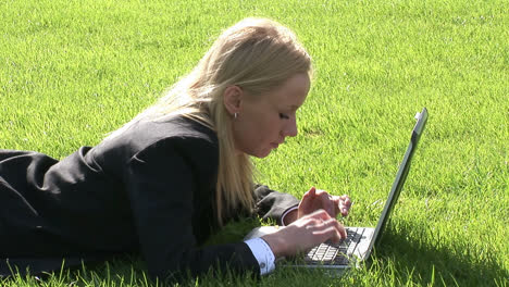 woman lying on grass using laptop computer