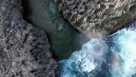 rotating aerial: man swims in angel's billibong on bali ocean coast