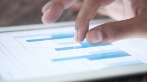 close-up of hand using tablet to analyze data graph