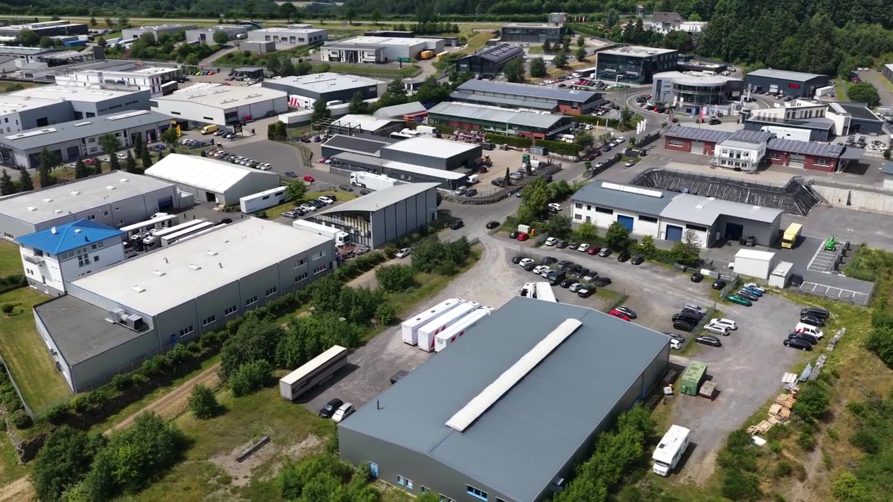 Luftfoto af motorsportsvirksomheder og bilfaciliteter ved siden af Nürburgring i Tyskland, der viser racer-værksteder, performance-virksomheder og baneinfrastruktur.