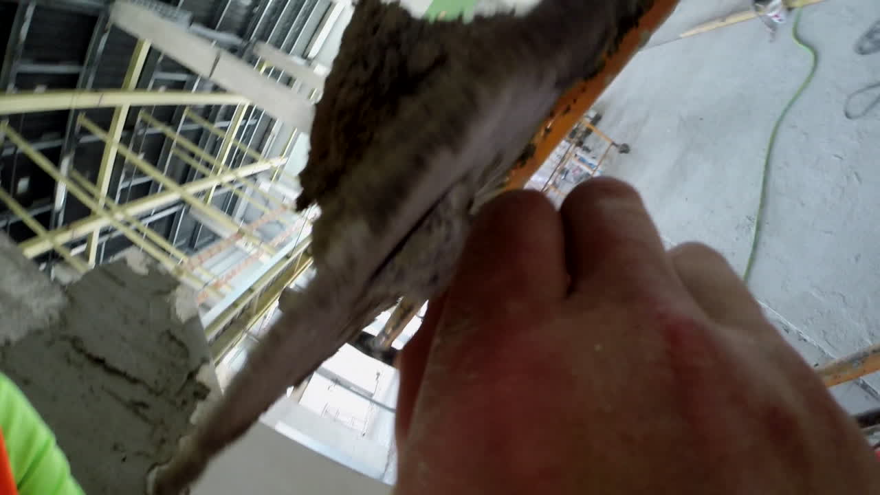 A worker applies fresh concrete to a column during construction works