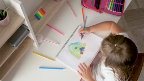 Overhead-of-a-little-girl-at-her-table-drawing