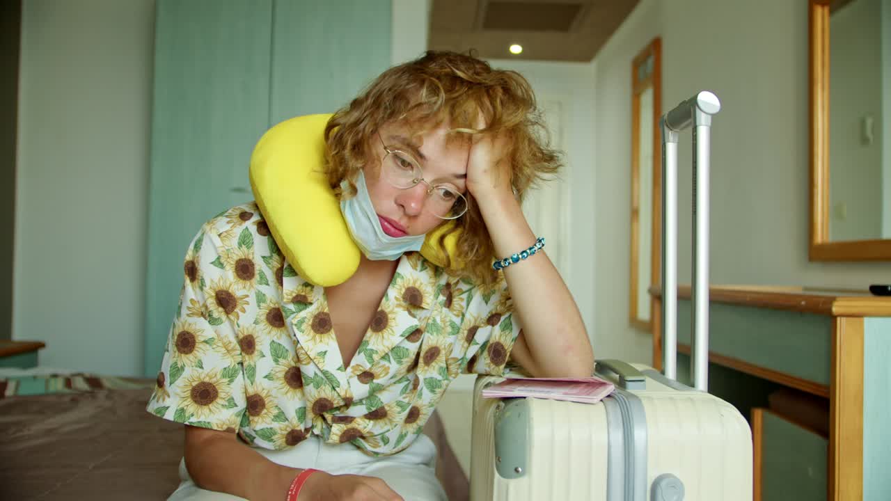 una mujer en una habitación de hotel con una máscara de protección y con una maleta, inmediatamente después del aeropuerto al hotel para la cuarentena. problema de vacaciones debido a la prueba de coronavirus