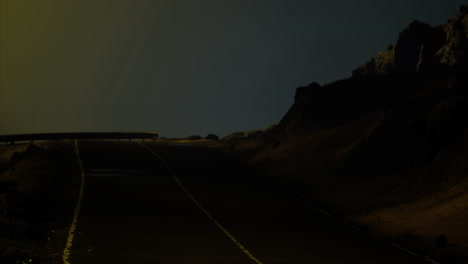 road leading into the night with rocky terrain and dim lighting