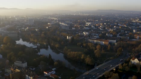 Drohnenaufnahme-Der-Stadtlandschaft-Von-Kassel-In-Schönem,-Weichem-Sonnenlicht-Und-Mit-Nebel-Bedeckt