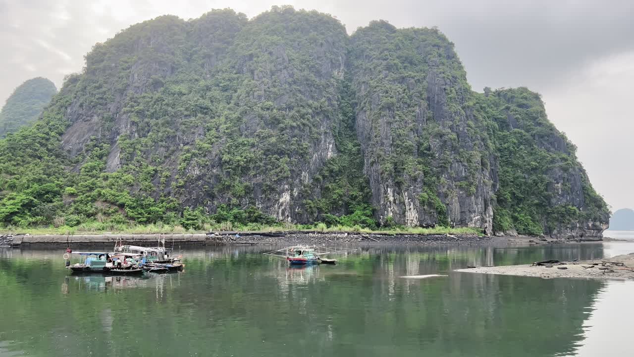 Traditional boats floating on calm waters near a lush limestone island in the Philippines.