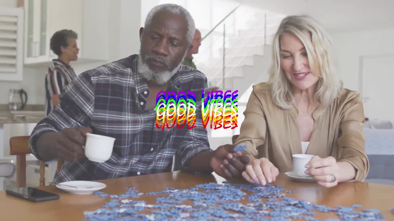 Colorful good vibes text against african american man and caucasian woman playing puzzle at home